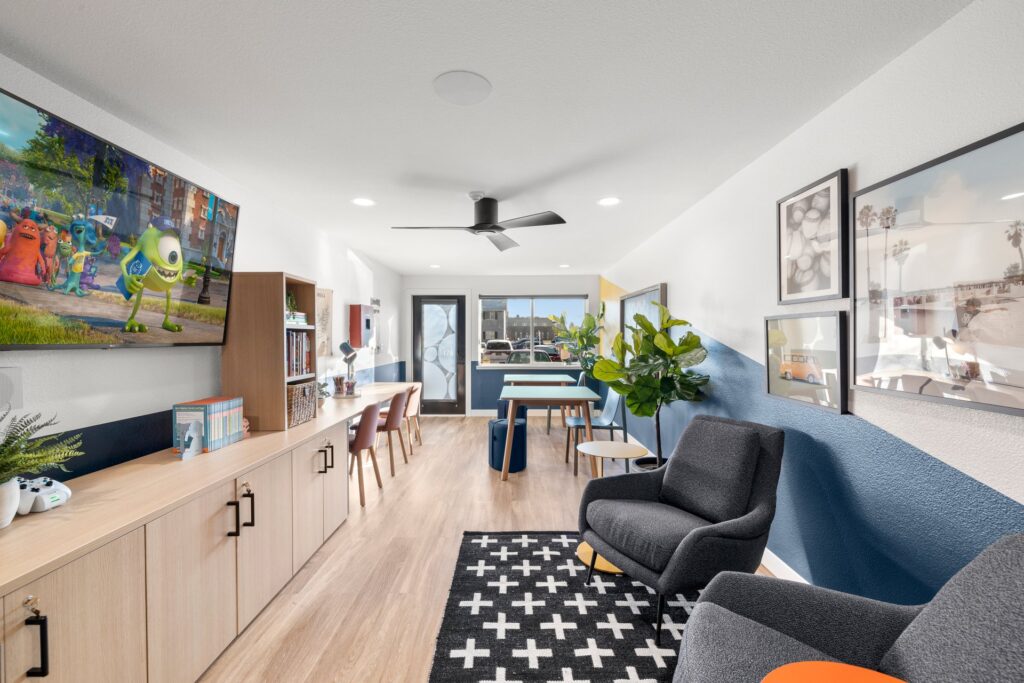 Kids club interior with desks and tables, coloring supplies and board games, couches and a TV