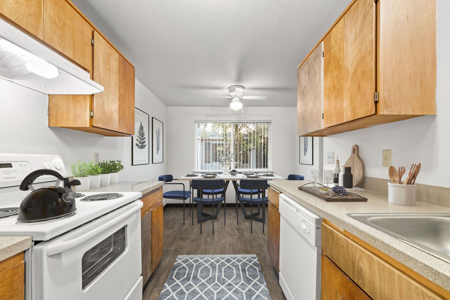 Kitchen with white appliances, wooden cabinets, and view into the dining area