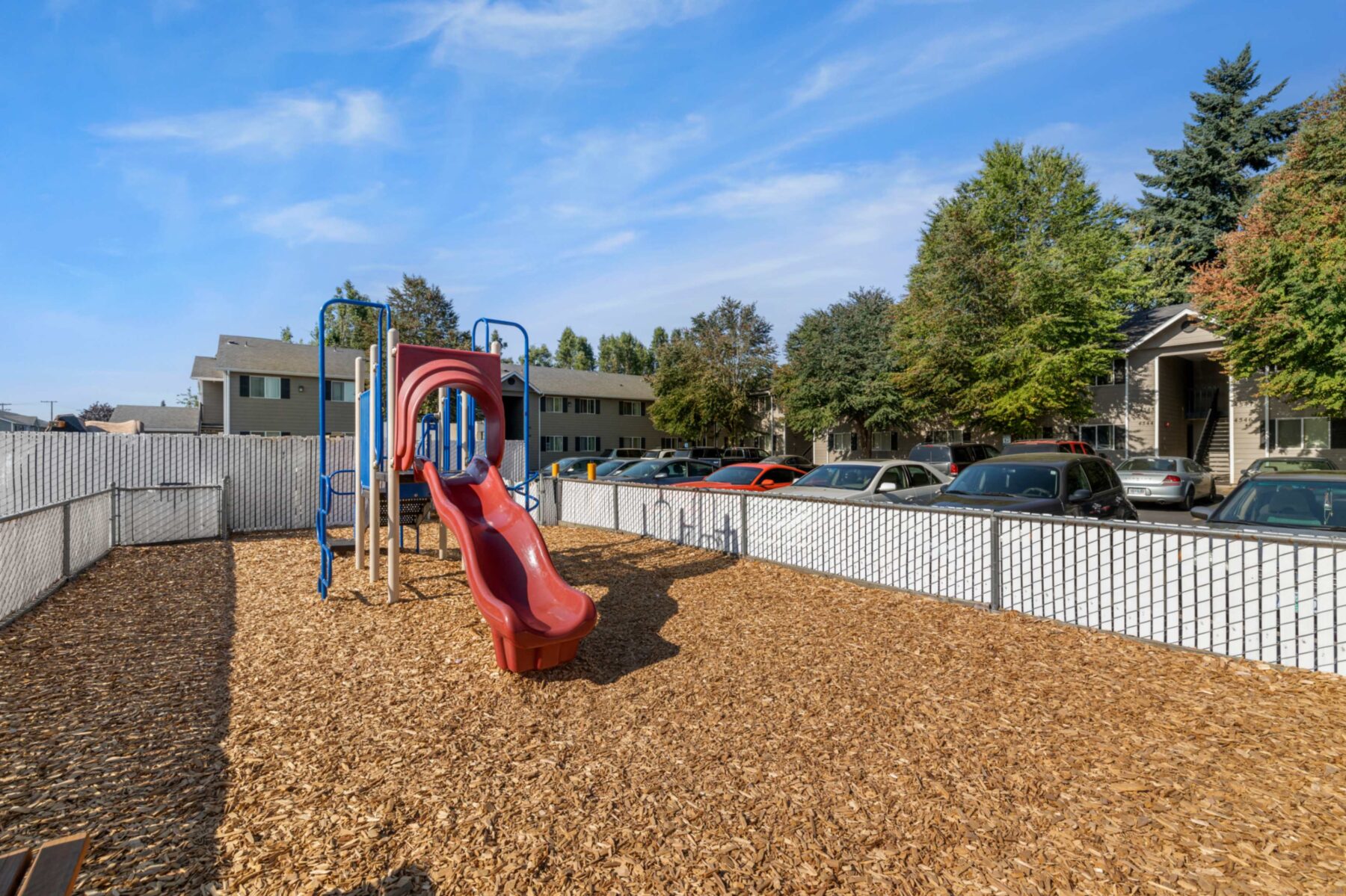 Fenced playground with climbing and slides
