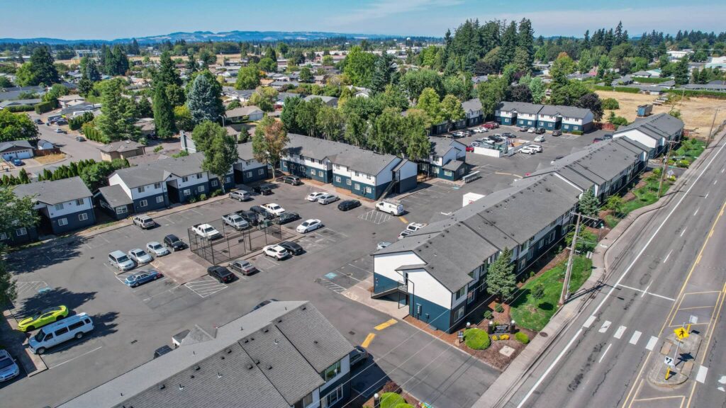 Aerial view of Lancaster Terrace apartments with rows of apartments, parking lots filled with cars, tree-lined streets, and surrounding greenery.