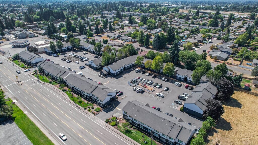 Aerial view of Lancaster Terrace apartments featuring several large L-shaped buildings with a parking lot, surrounded by trees and residential houses.