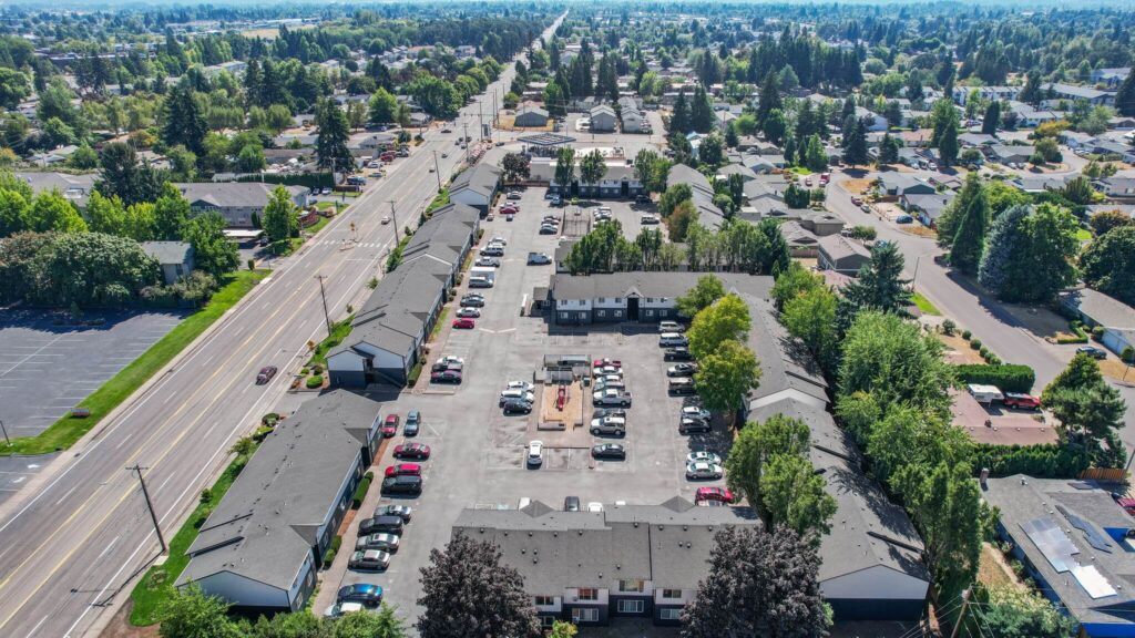 Aerial view of Lancaster Terrace apartments featuring several large L-shaped buildings with a parking lot, surrounded by trees and residential houses.