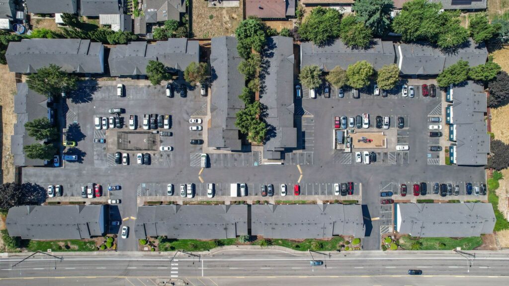 Aerial view of Lancaster Terrace apartments featuring several large L-shaped buildings with a parking lot, surrounded by trees and residential houses.