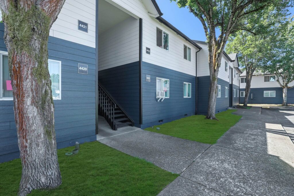Exterior of a two-story apartment building with a dark blue and white painting.